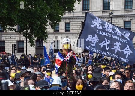 London, England, Großbritannien. 12.. Juni 2022. Ein Protestler schwenkt die Flagge „Hongkong befreien - Revolution unserer Zeit“. Tausende von Hongkongern versammelten sich auf dem Parlamentsplatz, um den dritten Jahrestag der brutalen Niederschlagung der Proteste in Hongkong durch die chinesische Regierung zu begehen. (Bild: © Vuk Valcic/ZUMA Press Wire) Stockfoto