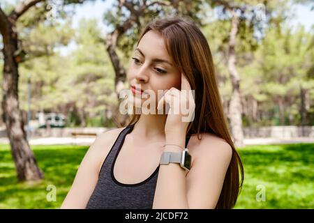 Junge schöne Frau trägt sportliche Kleidung im Stadtpark, im Freien Finger berühren Kopf tief in Gedanken, denken über wichtige Dinge. Hoffnung. Sadne Stockfoto