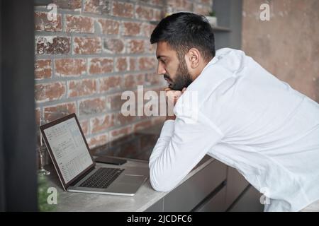 Junger Mann mit einem Laptop in der Küche. Stockfoto