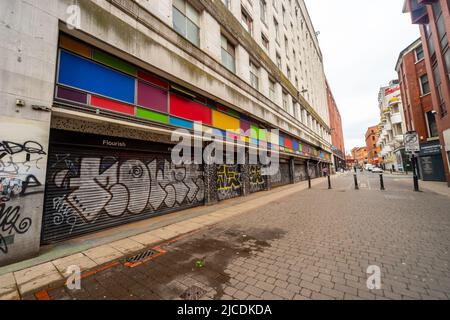 Sprühen Sie Graffiti und leuchtende Farben auf die geschlossenen Fenster eines Gebäudes in der TIB Street, Manchester, England, Großbritannien Stockfoto