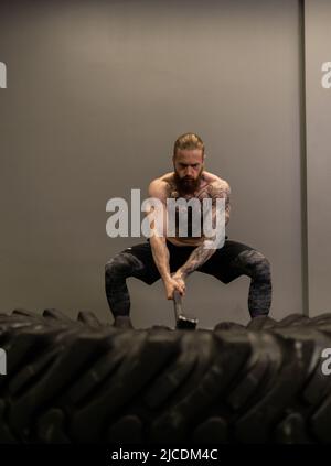 Vorschlaghammer Trucker Rad Straße Reifen Frau ersetzen junge Hammer Turnhalle, für Geräte Konzentration von Mann aus Muskeltraining, Mann Erwachsene Stockfoto