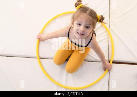 Kleines blondes Mädchen mit schwanzigen Schwänzen, das mit Hula Hoop spielt Stockfoto
