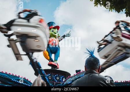 Rückseite eines Mannes mit einem Blue-Mohician-Haarschnitt, der vor der Cricket-Messe von Jiminy am Morpeth Fair Day, 2022. Juni, Northumberland, steht Stockfoto