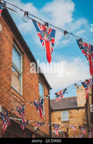 Eine schmale Straße in Morpeth, in der Union Jack-Ammer am 2022. Juni, Northumberland, aufgehängt hat Stockfoto