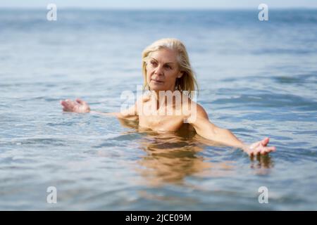 Elderige Frau in gutem Zustand, die im Meer baden. Stockfoto