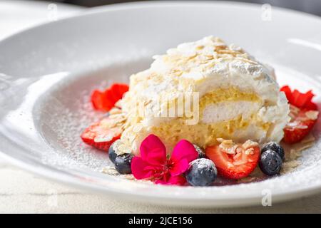 Meringuerolle mit Erdbeeren, Blaubeeren, Himbeeren und Preiselbeeren. Dessert mit frischen Beeren auf dem Tisch dekoriert. Stockfoto