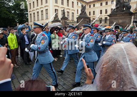 Touristen beobachten die Zeremonie der Wachablösung (Hradní Stráž) bei Regen vor der Prager Burg auf dem Hradčanské-Platz in Prag, Tschechische Republik. Stockfoto