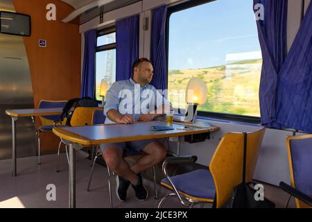 Hübscher Mann, der mit dem Zug reist und aus dem Fenster blickt. Stockfoto Stockfoto