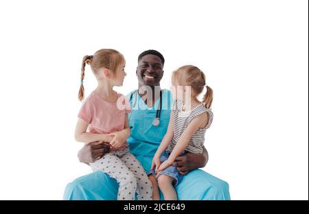 Ein amerikanischer Kinderarzt umarmt zwei kleine Mädchen, die auf seinem Schoß auf weißem Hintergrund sitzen Stockfoto