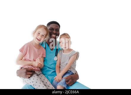 Ein amerikanischer Kinderarzt umarmt zwei kleine Mädchen, die auf seinem Schoß auf weißem Hintergrund sitzen Stockfoto