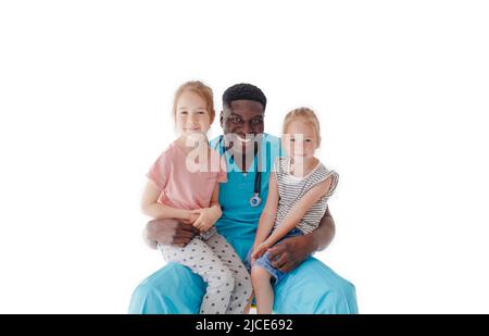 Ein amerikanischer Kinderarzt umarmt zwei kleine Mädchen, die auf seinem Schoß auf weißem Hintergrund sitzen Stockfoto