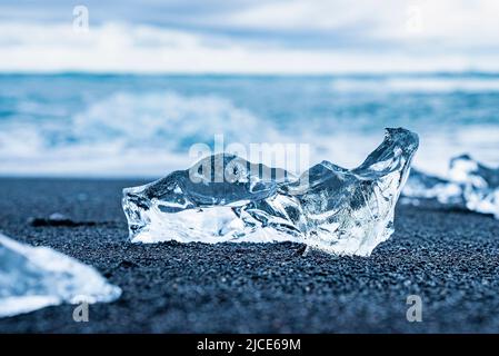 Nahaufnahme von glänzendem Eisbrocken am schwarzen Sandstrand von Diamond Beach Stockfoto