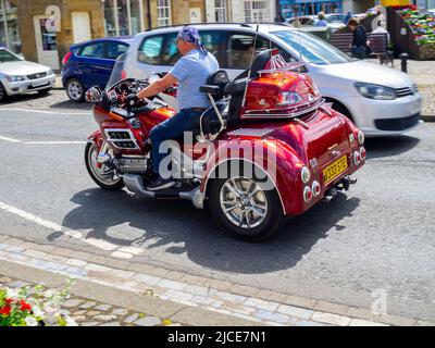 Mann, der ein Honda Gold Wing Enthusiasten anspruchsvolle Touren Roadster sechs Zylinder Kreuzfahrt Motor Dreirad entlang der High Street in Stokesley North fahren Stockfoto