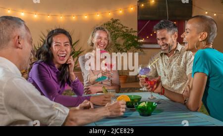 Fröhliche Freunde trinken Cocktails. Ältere Menschen haben Spaß Sommernacht. Lifestyle- und Nightlife-Konzept. Stockfoto