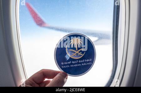 6. Dezember 2021, Jeddah, Saudi-Arabien. Das Emblem der Fluggesellschaft Saudi Arabian Airlines auf dem Hintergrund des Fensters des Flugzeugs. Stockfoto