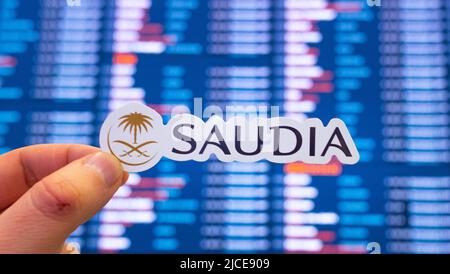 11. Dezember 2021, Jeddah, Saudi-Arabien. Das Emblem der Fluggesellschaft Saudia vor dem Hintergrund einer elektronischen Tafel mit einem Flugplan am Stockfoto