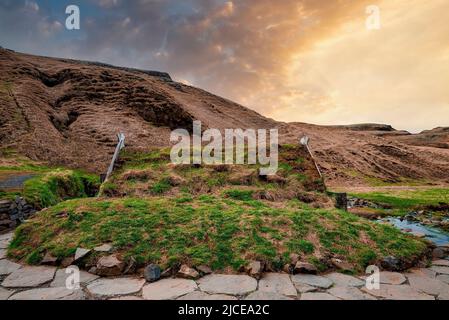 Blick auf Turf House und geothermischen Hot Pot in Hrunalaug auf Berg gegen den Himmel Stockfoto