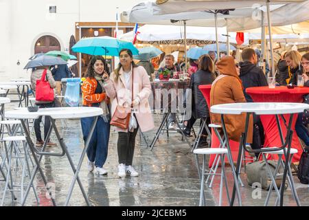 Junge Frauen, die im Regen mit Sonnenschirm spazieren, Piazza di Santa Croce, Florenz (Florenz), Region Toskana, Italien Stockfoto