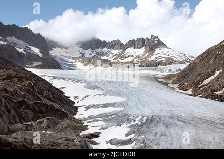 Rhonegletscher auf dem Gipfel des Berges mit sichtbarer Eisoberfläche, Schnee und Rissen. Malerische hochalpen Berge und eine raue Landschaft. Stockfoto