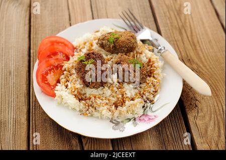 Drei Linsen-Patties mit Reis, Tomaten und Mikrogemüse auf weißem Teller horizontal Stockfoto