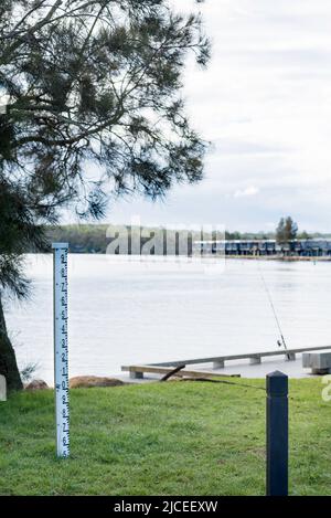 Ein Tiefenmarker in der Nähe von Ferienhütten, die am Ufer des Lake Conjola an der australischen Südküste, NSW, gebaut wurden Stockfoto