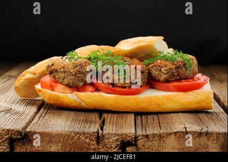 Linsenpastete-Sandwich mit Tomaten- und Karottengrün in altem Holzbrett horizontal Stockfoto