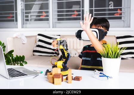 Virtual Reality Simulator. Asiatische Kind Junge mit VR-Brille auf Roboterarm in der Werkstatt, Kind lernen Programmierer steuern Roboterarm mit Sensoren zu holen Stockfoto