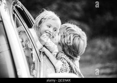 Glücklich lächelndes kleines Mädchen sagt Auf Wiedersehen zu kleinen Freund, der lange Zeit segelt. Gibt einen warmen Kuss. Ein Paar sagte vor der Autofahrt Auf Wiedersehen Stockfoto