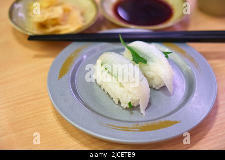 Nahaufnahme von Engawa Sushi oder Muskel von Plattfisch oder einäugigen Fischen, Sushi auf einem runden Teller auf dem Tisch im Restaurant. Nahaufnahme der japanischen Küche. Stockfoto