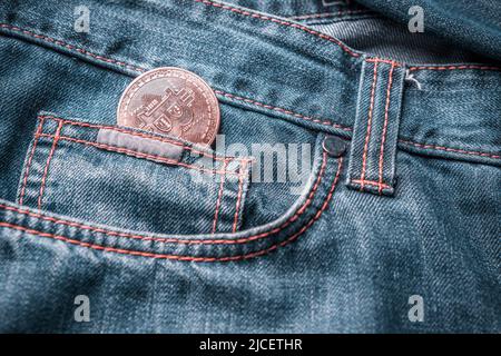 Bitcoin in einer kleinen Jeans-Tasche. Virtuelles Geld in der Jeans-Tasche. Stockfoto