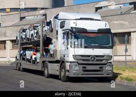 SANKT PETERSBURG, RUSSLAND - 17. JULI 2021: Autotransporter 'Mercedes Benz' mit neuen Autos der Carsharing-Firma 'Delimobil' wartet auf Entladung Stockfoto