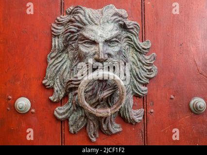 Kunstvoller Türklopfer mit Gesicht und Ring an einer rötlich-braunen Holztür in Cartagena, Kolumbien, UNESCO-Weltkulturerbe Stockfoto