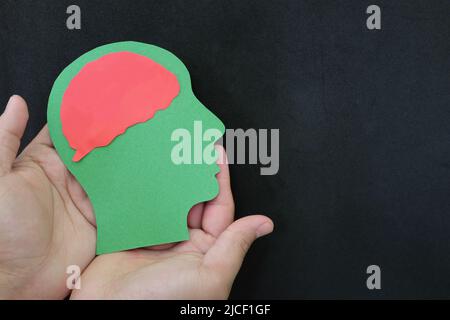 Psychische Gesundheitsversorgung und Bekämpfung von Depressionen Konzept. Hand hält menschlichen Kopf mit Gehirn in dunkelschwarzem Hintergrund. Stockfoto