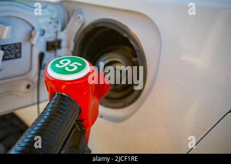 Rote Düsenpumpe Gun Benzin von der Ölpumpe im Autotank zum Tanken. Stockfoto