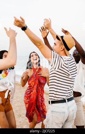 Fröhliche junge Freunde tanzen auf Sommerparty am Strand Stockfoto