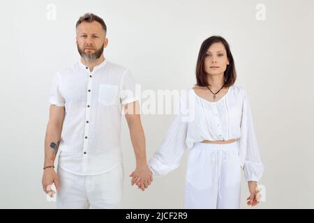 Bärtiger Mann und Frau, Familie in weißen Modekleidern, die Hände zusammenhaltend. Familienunternehmen, Vertrauensverhältnis Stockfoto