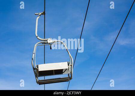 Oberammergau, Deutschland - 31. Okt 2021: Blick auf einen einzelnen, hängenden Sessellift. Blauer Himmel im Hintergrund, keine Menschen. Stockfoto