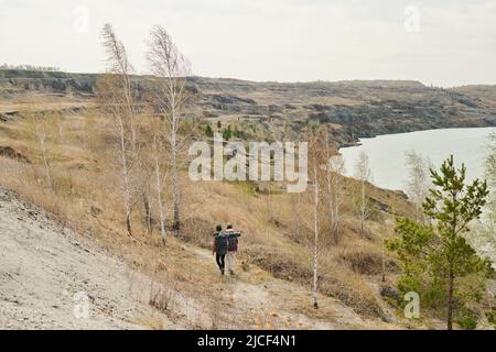 Extreme Langaufnahme von zwei unkenntlichen Touristen mit Rucksack Wandern rund um Steinbruch See am Frühlingstag Stockfoto