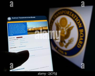 Person, die das Smartphone mit der Website des US Surface Transportation Board (STB) auf dem Bildschirm vor der Dichtung hält. Konzentrieren Sie sich auf die Mitte des Telefondisplays. Stockfoto