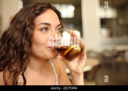 Glückliche Frau, die in einem Café aus Glas Limonade trinkt Stockfoto