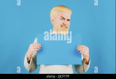 Porträt des Mannes zeigt blau leer Schild mit Copy Space Bereich für Slogan oder Text. Der junge Mann zeigt ein Blatt Papier in der Kamera auf einer Farbe Stockfoto