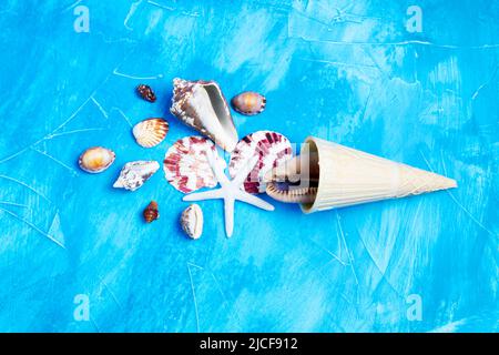 Eiswaffelkegel und Muscheln auf blauem Hintergrund, die Wasser imitieren. Kreatives Sommerurlaubskonzept. Stockfoto