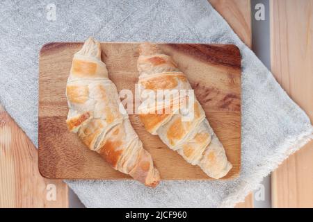 Komposition mit hausgemachten Croissants auf einem Holzbrett. Stockfoto