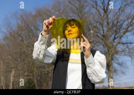 Schwarz haarige Frau, die durch gelben Farbfilm schaut Stockfoto