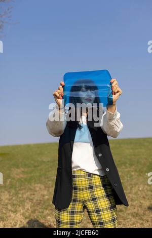 Modisch gekleidete Frau mit blauer Farbfolie Stockfoto