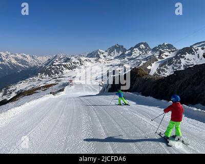 Skigebiet Silvretta Ski Arena Ischgl/Samnaun, Skifahrer, Kinder von hinten, bunte Kleidung, Blick auf Idalp, Samnaun, Winter, Natur, Berge, blauer Himmel, Paznaun, Ischgl, Tirol, Österreich Stockfoto