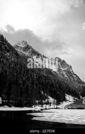 Eisbruch am Ferchensee in den bayerischen Alpen oberhalb von Mittenwald im Frühjahr. Im Hintergrund das Wettersteingebirge mit dichten Wolken und Neuschnee. Stockfoto