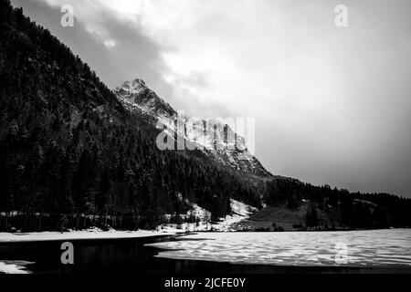 Eisbruch am Ferchensee in den bayerischen Alpen oberhalb von Mittenwald im Frühjahr. Im Hintergrund das Wettersteingebirge mit dichten Wolken und Neuschnee. Stockfoto