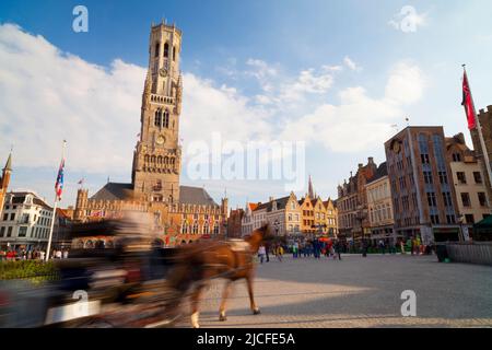 Verschwommene Bewegung der Pferdekutsche auf dem historischen Marktplatz von Brügge, Westflandern, Belgien Stockfoto