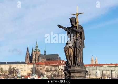 St. Johannes der Täufer, Skulptur des heiligen auf der Karlsbrücke, Prager Burg mit St.-Veits-Kathedrale dahinter, Prag, Tschechische Republik Stockfoto